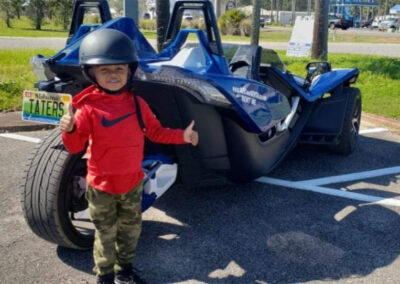 little boy with helmet on ready to ride in a blue slingshot rental