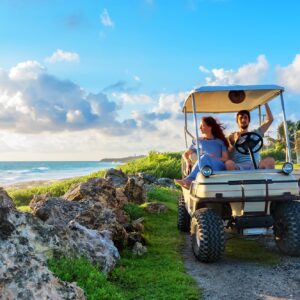 couple driving a golf cart by beach