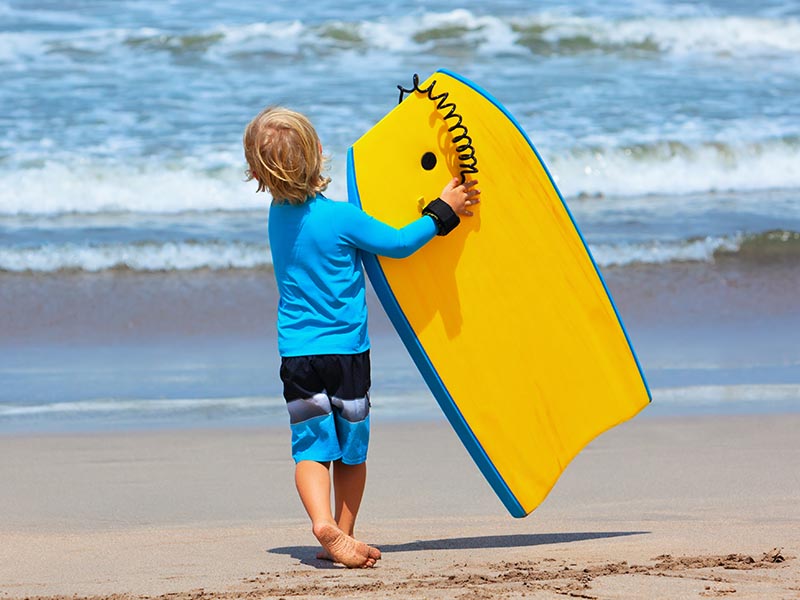 Baby boy - little surfer run with bodyboard to sea for riding on